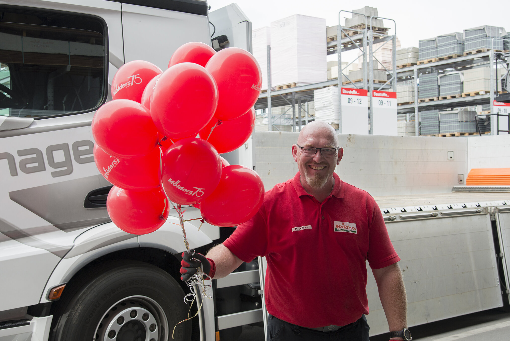 Lagermitarbeiter hält rote Luftballons in der Hand