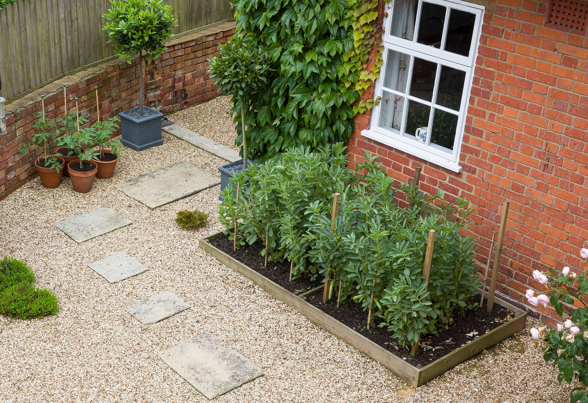 Innenhof zeigt verschiedene Gartenbaustoffe wie Schotter, Kies, Platten und Hochbeeten