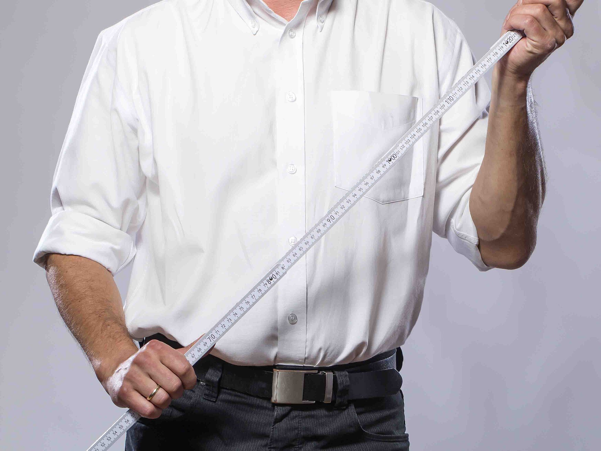 Person in weißem Hemd hält einen ausgeklappten Zollstock in beiden Händen