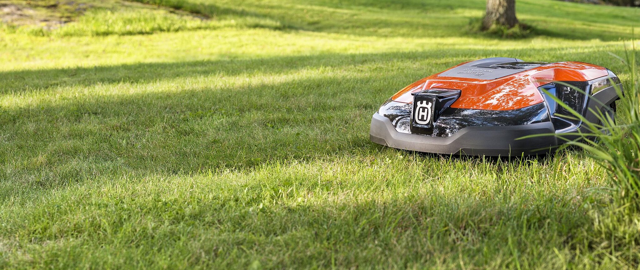 Husqvarna Mähroboter in der Farbe Orange fährt über eine Rasenfläche