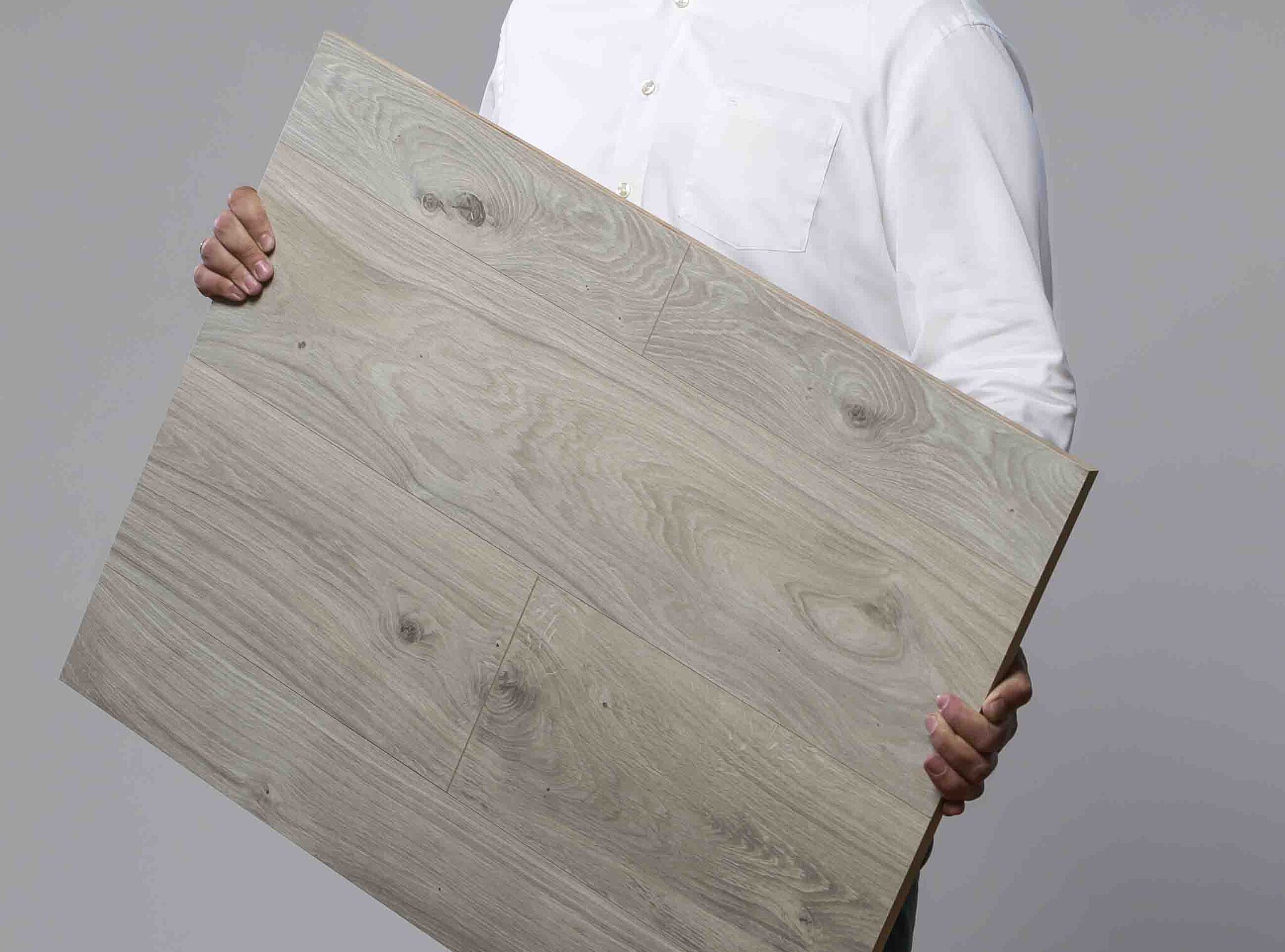 Person in weißem Hemd hält eine Holzplatte in beiden Händen