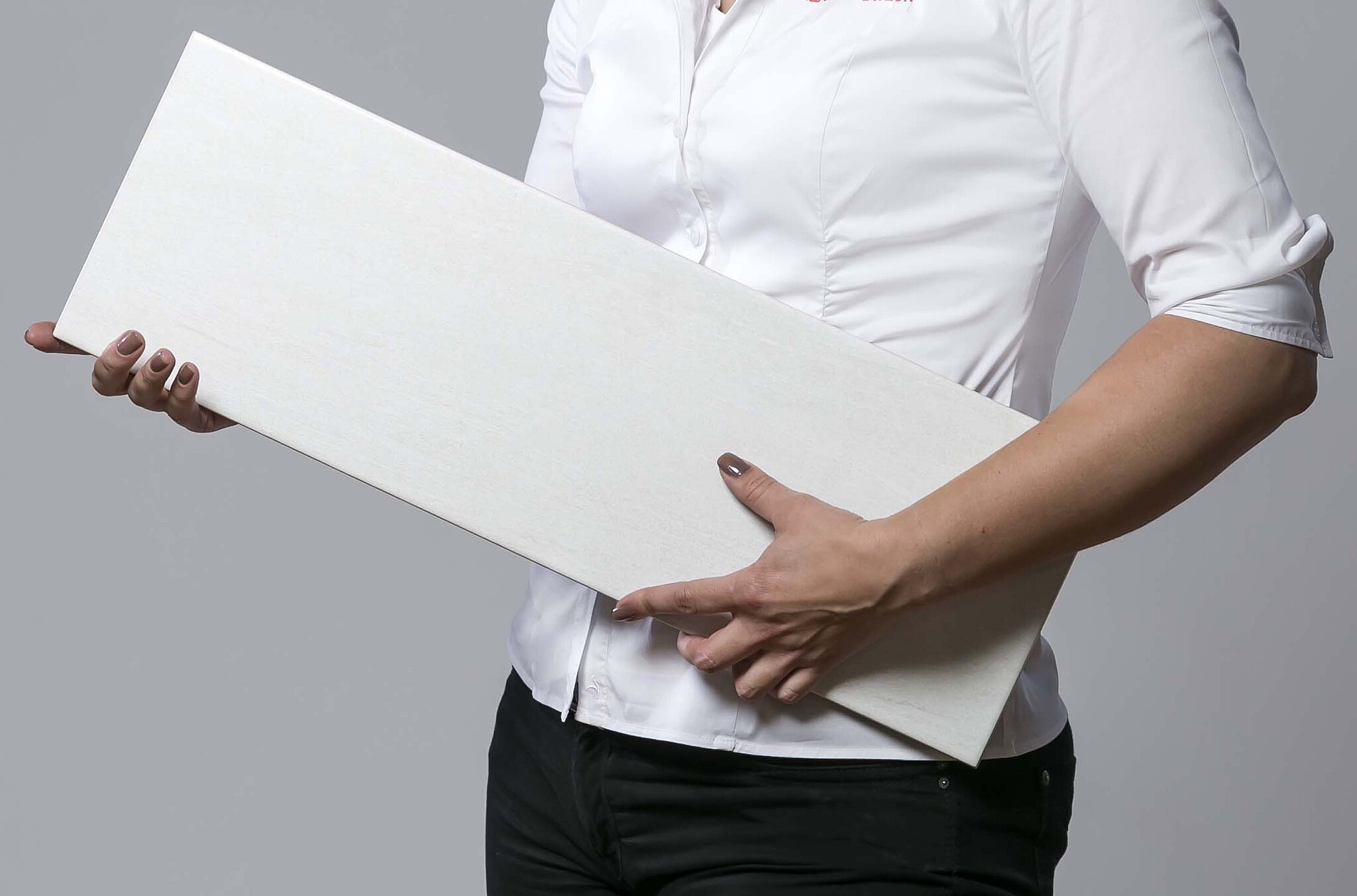 Person in weißem Hemd hält eine rechteckige Fliese in beiden Händen